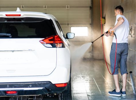 Young man spraying his car clean