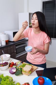 young woman in kitchen preparing salad dressing in bowl