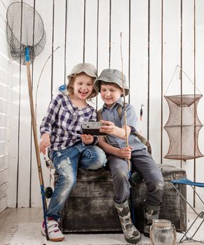 two little smiling children making selfie sitting on old big chest