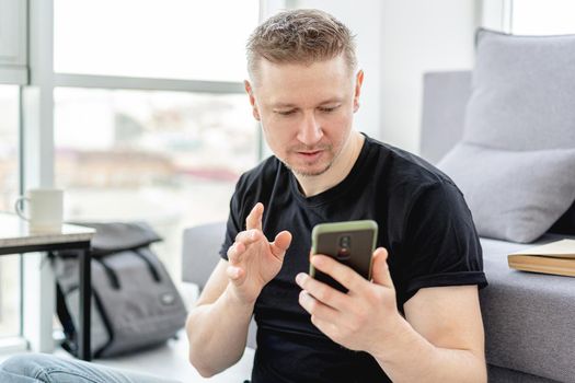 Smiling man looking into smart phone indoors