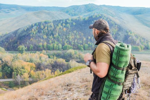 Man hiker with backpack at the top of the hill looking at landscape.