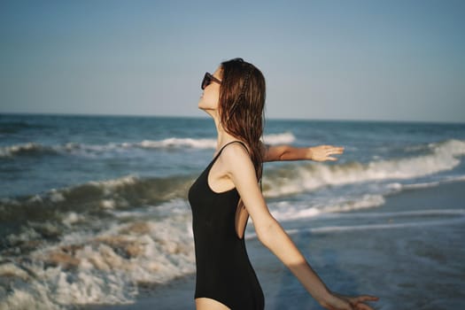 pretty woman in black swimsuit posing sun walking on the beach. High quality photo