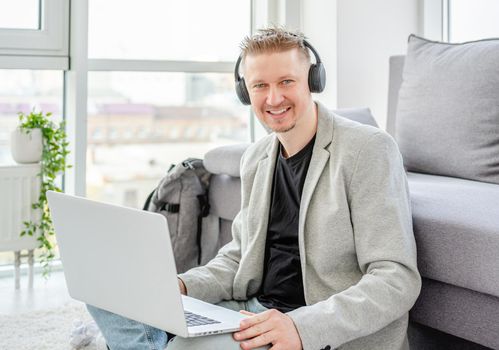 Happy man working on laptop in light apartment