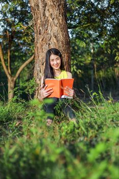 young woman sitting and reading a book in the park