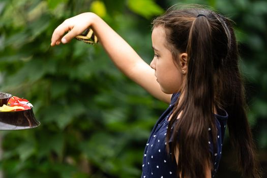 Little girl holding butterfly in her hand.