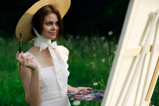 Woman in white dress artist easel painting nature landscape. High quality photo