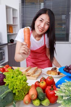 woman holding a carrot in kitchen room at home