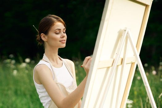 woman artist paints a picture near easel outdoors landscape creative. High quality photo