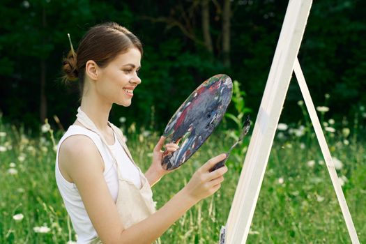 cheerful woman paints a picture palette nature landscape. High quality photo