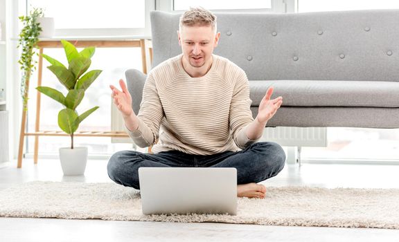 Man freelancer working at home with laptop and surprised holding his hands up. Remote work on distance in pandemic time