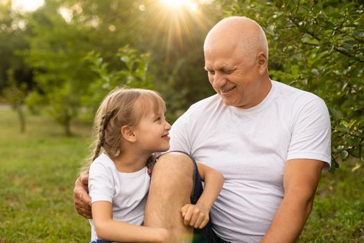 Little girl spending time with grandfather in the park.