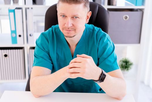 Handsome doctor sitting in light office