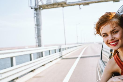 cheerful woman peeking out of the car window trip road travel. High quality photo