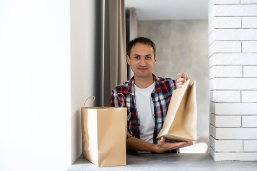 delivery, mail and people concept - happy man delivering food in disposable paper bag to customer home