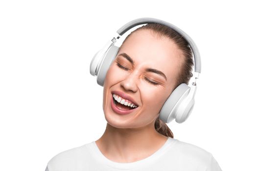 Singing woman with closed eyes in headphones over white background.