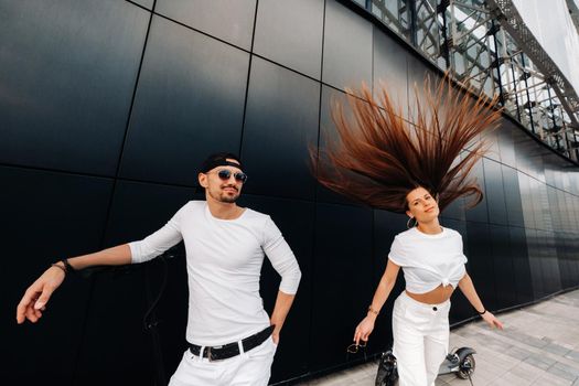 A girl and a guy are walking on electric scooters around the city, a couple in love on scooters