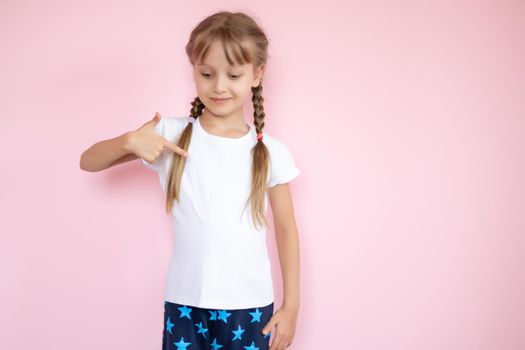 Pretty little girl in a white t-shirt smiling on a pink background
