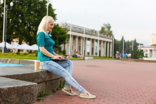 happy young student woman with laptop in city park study