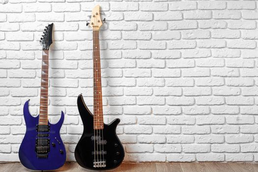 Set of guitars on the floor against white brick wall, copy space
