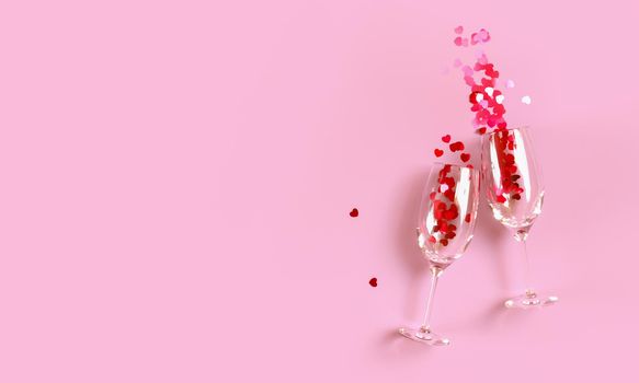 Two clinking champagne glasses with splash of red heart shaped confetti over pink background. Overhead view, copy space, 3D rendering illustration.