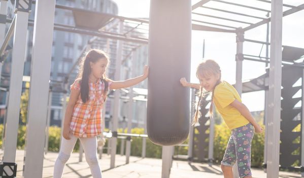 Two cute little girls having fun on a playground outdoors in summer. Sport activities for kids.