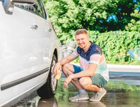 Man cleaning car handle with rag during car wash