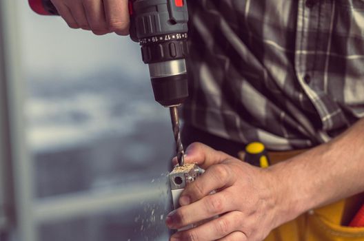 Man working making holes in board with drill during process of furniture manufacturing