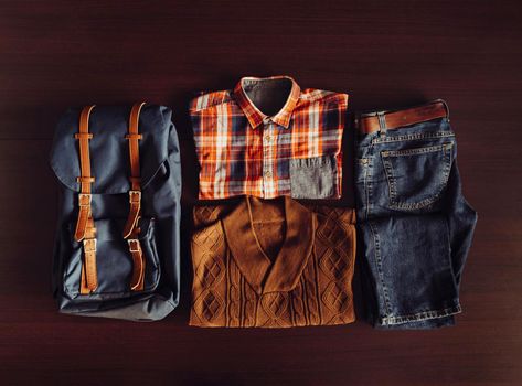 Set of male clothing and backpack in hipster style on wooden background, top view