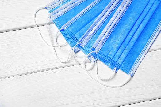 Blue medical face masks on white wooden background