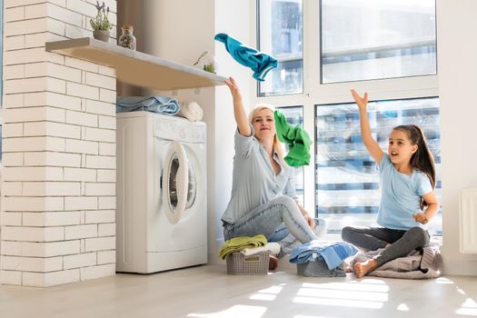 Young housewife and little girl doing laundry together