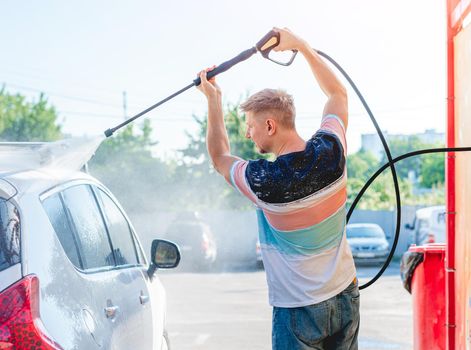 Man is washing car with high pressure water