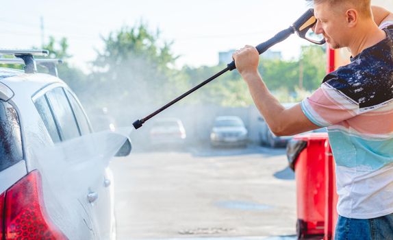 Man is washing car with high pressure water