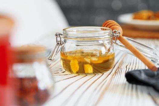 Glass jar of honey on wooden kitchen table, close up