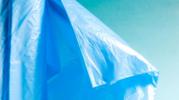 One roll of plastic garbage bags in blue on a blue background. Bags that are designed to accommodate garbage in them and used at home and placed in various garbage containers