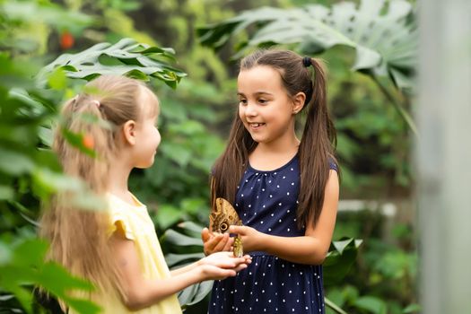 two little girls with butterflies in a greenhouse