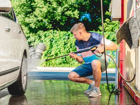 Man is washing car with high pressure water