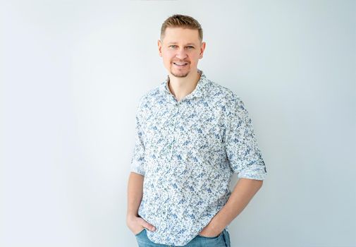 Smiling man posing with hands in pockets indoors
