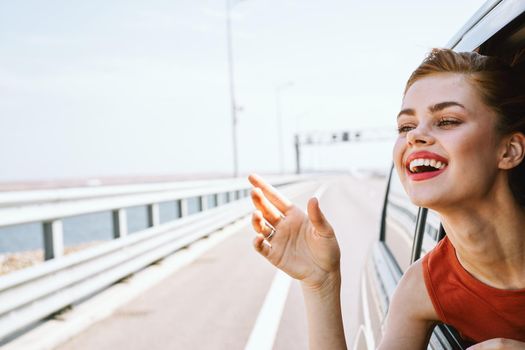 cheerful woman peeking out of the car window trip road travel. High quality photo