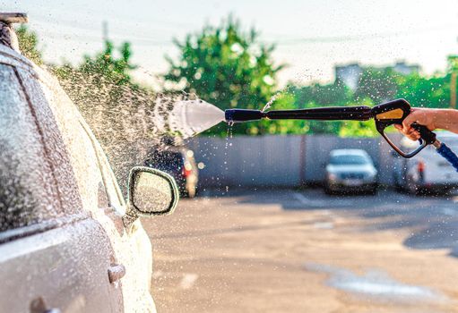 Applying washing foam on car at car wash station