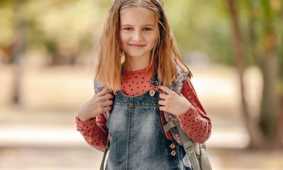 Preteen school girl with backpack closeup portrait outdoors. Pretty pupil female kid after education class in autumn park