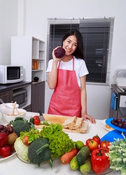 happy woman holding purple cabbage in kitchen room at home