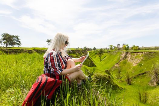 woman hiker use tablet pc sit on seaside mountain peak rock