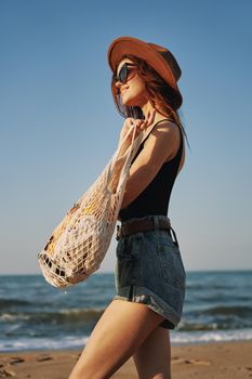 cheerful woman in a hat with sunglasses walking with a bag. High quality photo