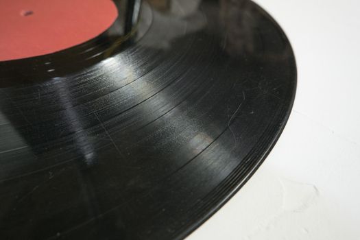 Old vinyl record in paper case on white marble background.