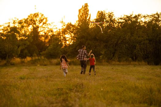 happy family father and child daughter run with a kite on meadow