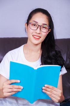 young woman reading a book on sofa at home