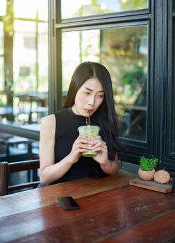 young woman dinking ice green tea latte in the cafe