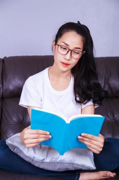 young woman reading a book on sofa at home