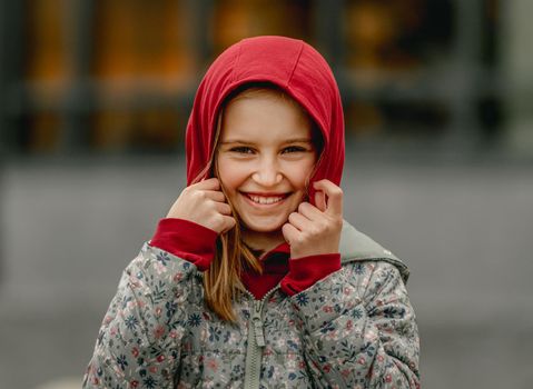 Preteen girl wearing hood at the street at autumn. Pretty female kid portrait outdoors