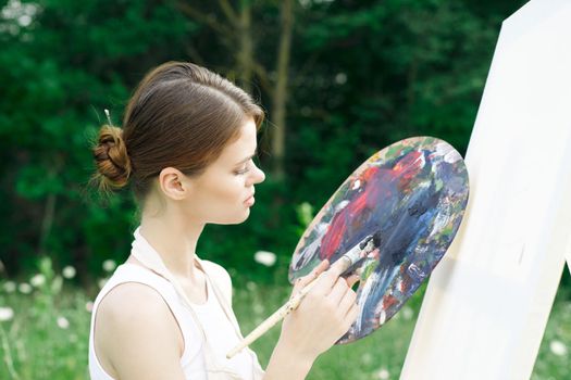 woman artist paints palette easel nature drawing. High quality photo